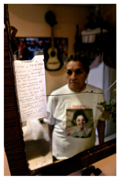 Hortensia Enriquez is reflected in a mirror in her daughter’s, Ericka Noemi bedroom. Enriquez has not removed any items from the room, since Noemi went missing on her way to get a haircut on December 11, 2000 in Chuhuahua City. In the mirror there is a list of goals that Noemi wrote. One of her goals was to work hard to pay off her tuition and read Plato. March 27, 2004 Photo by Christ Chavez 